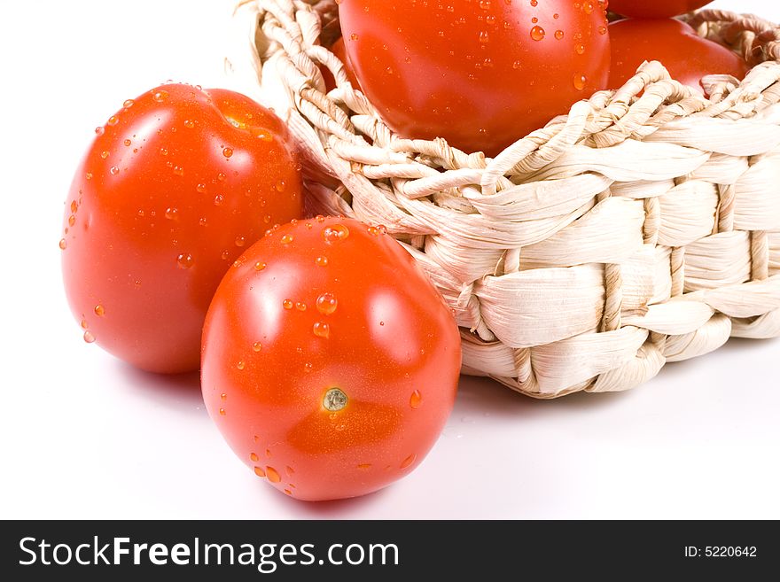 Fresh tomatoes  with waterdrops in a basket isolated on a white background. Fresh tomatoes  with waterdrops in a basket isolated on a white background.