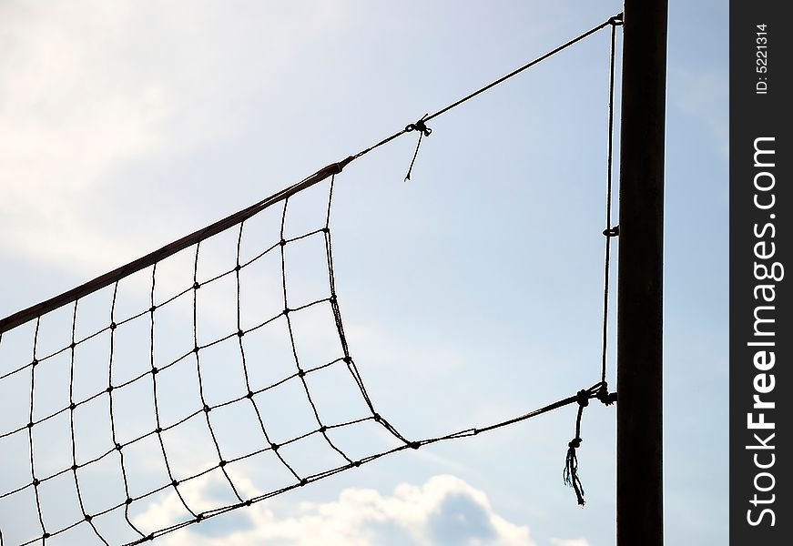 Volleyball net with blue sky and clouds in the background