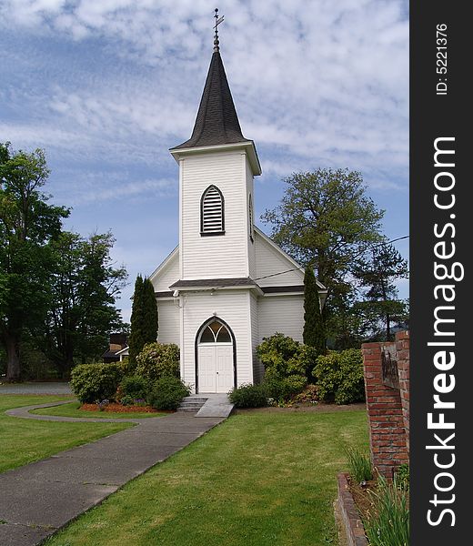 Front view of a country church with blue sky and light fluffy clouds. Front view of a country church with blue sky and light fluffy clouds.