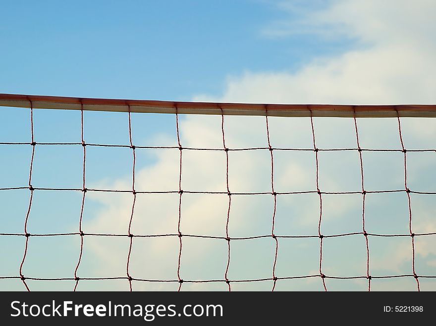 Volleyball net with blue sky and clouds in the background