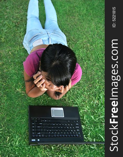 Girl and laptop on the green grass