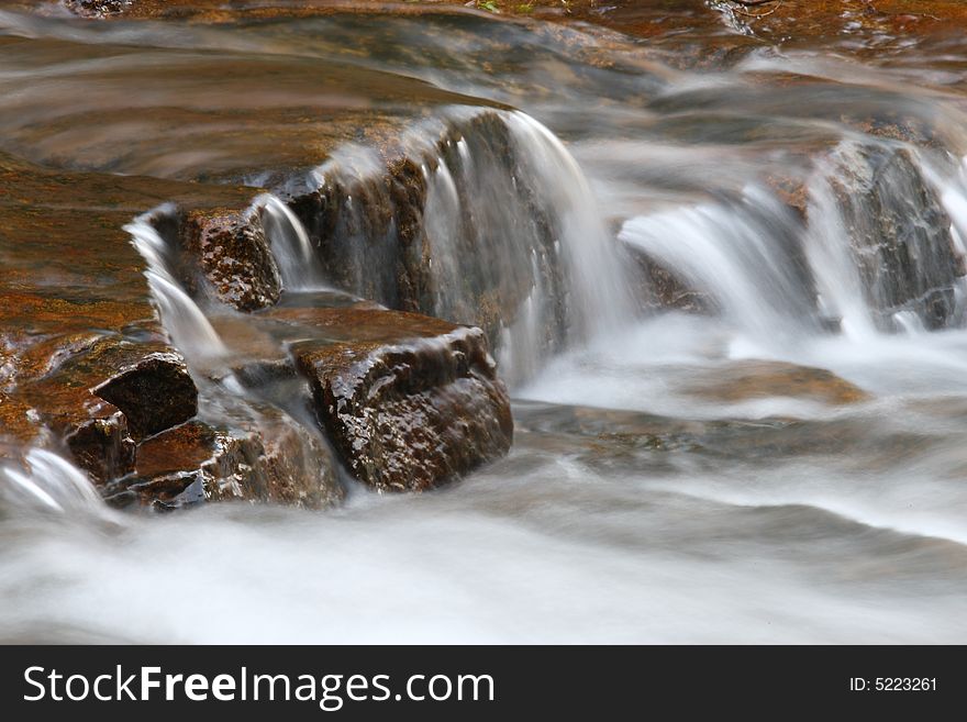 The water which flowing between rocks. The water which flowing between rocks