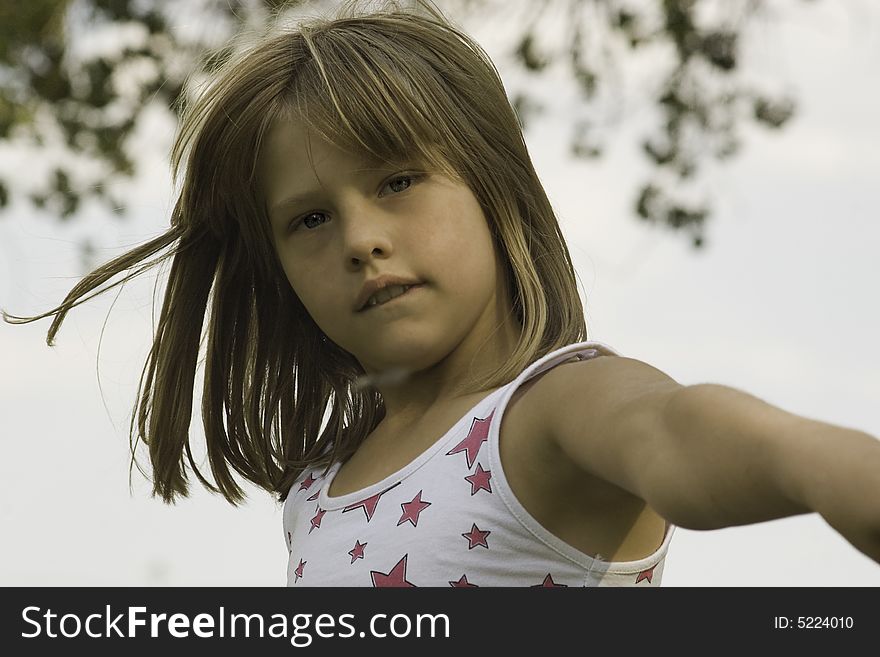 A Young girl playing in a park, wind blowing through her hair.