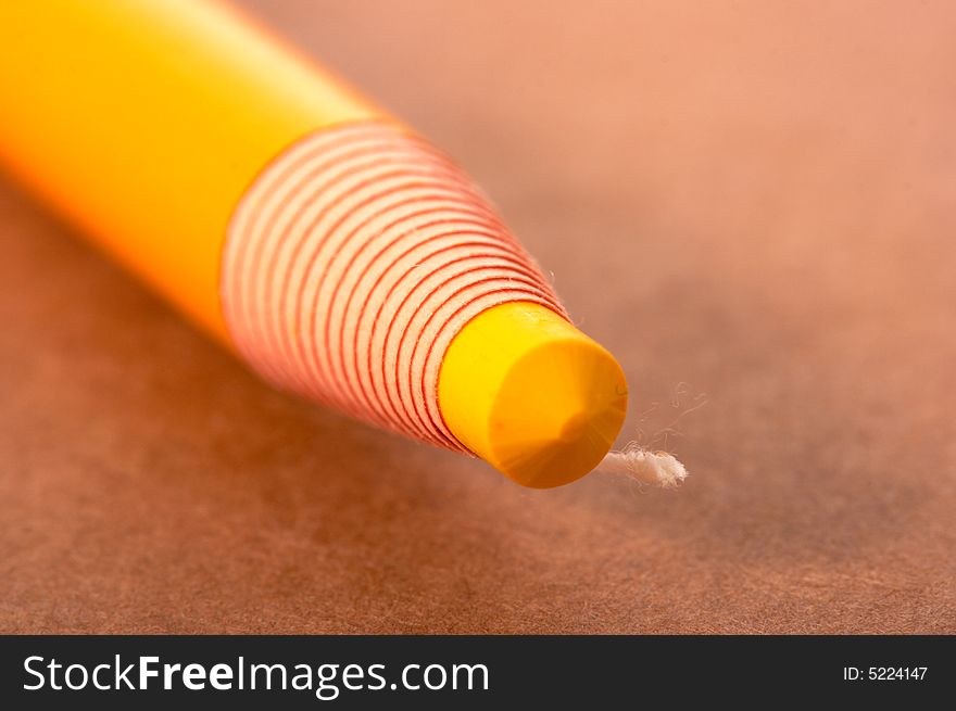 Yellow pencil on a brown sheet of paper. Yellow pencil on a brown sheet of paper