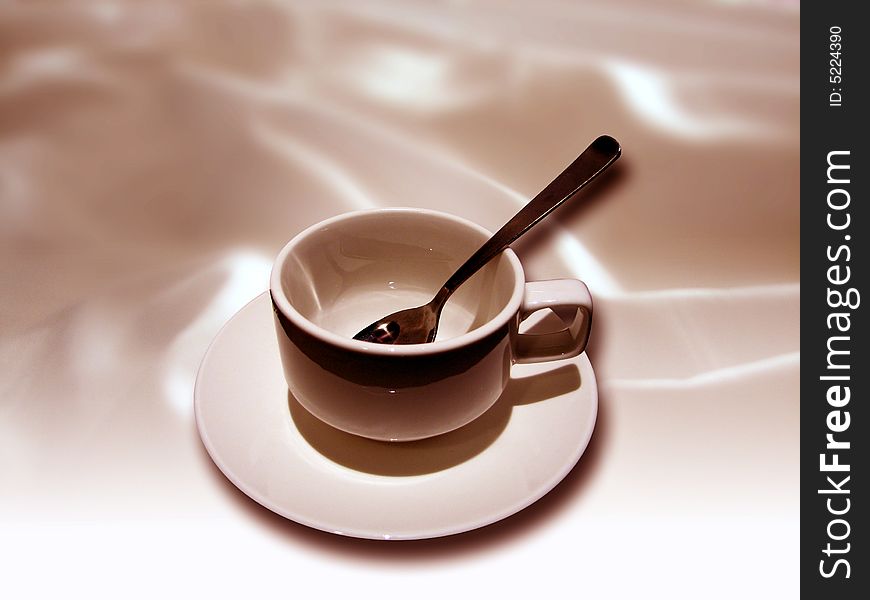 A cup and tea spoon with textile background