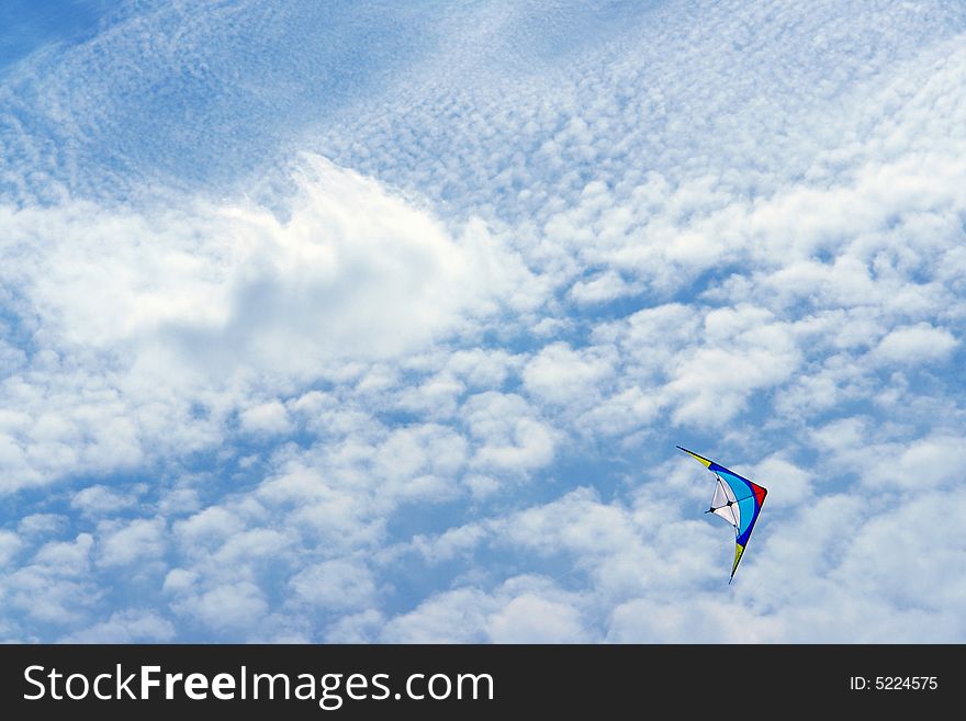 Colored kite agaisnt in a blue sky with clouds. Colored kite agaisnt in a blue sky with clouds