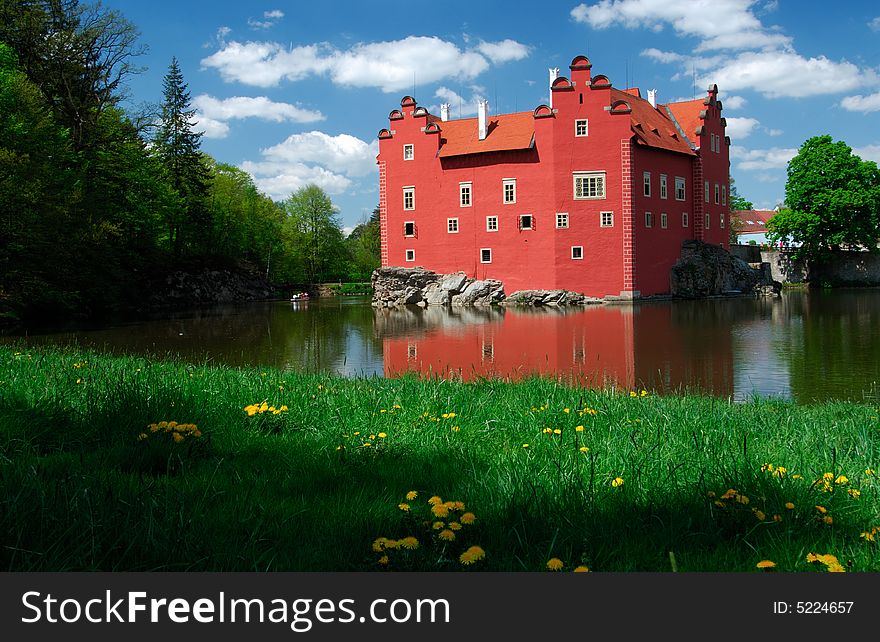 Castle Cervena Lhota built up in manor house style with red colored walls at little island surrounded by water of pond in south part of the Czech Republic