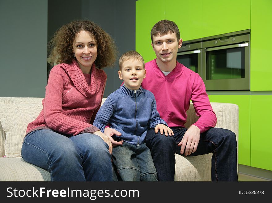 Family of three sits on sofa. Family of three sits on sofa