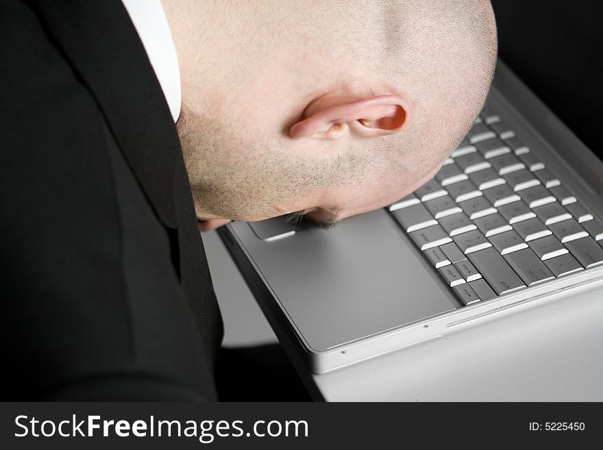 A stressed bald businessman with his forehead resting on the laptop computer keyboard. A stressed bald businessman with his forehead resting on the laptop computer keyboard.