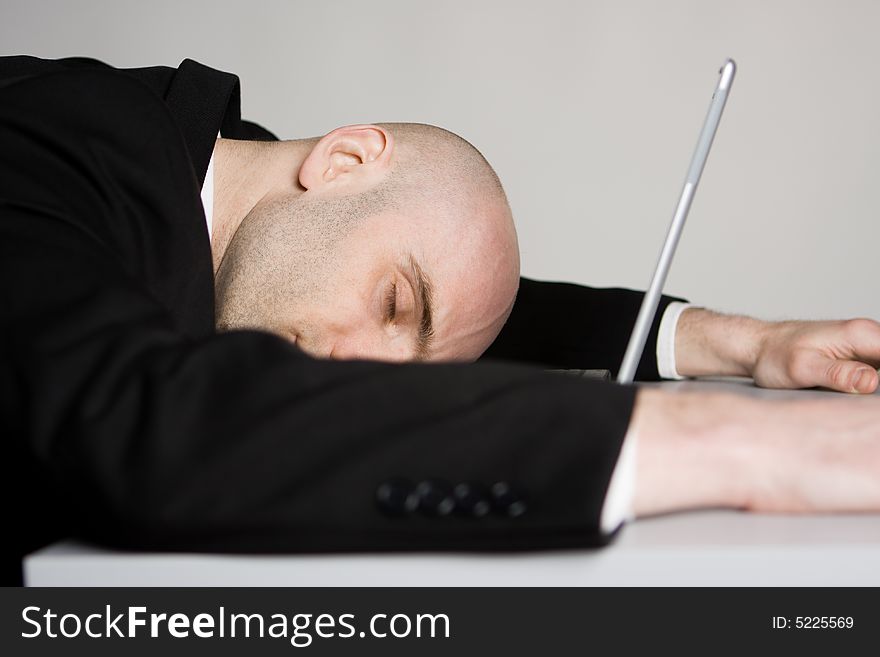 A stressed bald businessman with his forehead resting on the laptop computer keyboard. A stressed bald businessman with his forehead resting on the laptop computer keyboard.