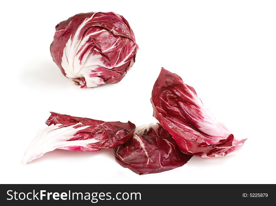 Fresh deep red white veined radicchio leaves with head in background. Fresh deep red white veined radicchio leaves with head in background