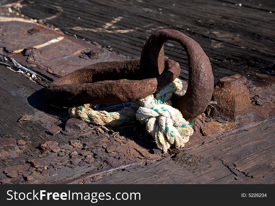 Close up detail of worn iron rings and rope on old dock. Close up detail of worn iron rings and rope on old dock