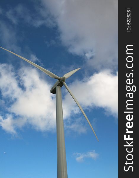 Picture of upper half of a wind turbine against blue cloudy sky