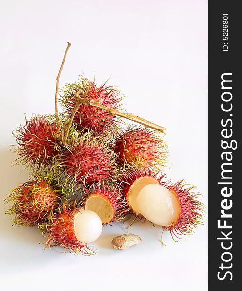 Still life of rambutans still attached to their branches, whole, peeled, and a single seed