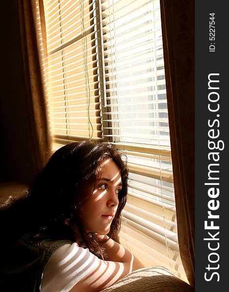 Young beautiful teen girl daydreaming looking out window. Young beautiful teen girl daydreaming looking out window