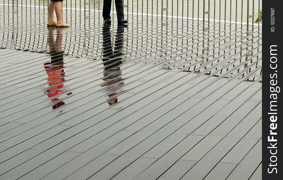 A couple reflected on the wet boardwalk after a tropical afternoon convectional shower. A couple reflected on the wet boardwalk after a tropical afternoon convectional shower