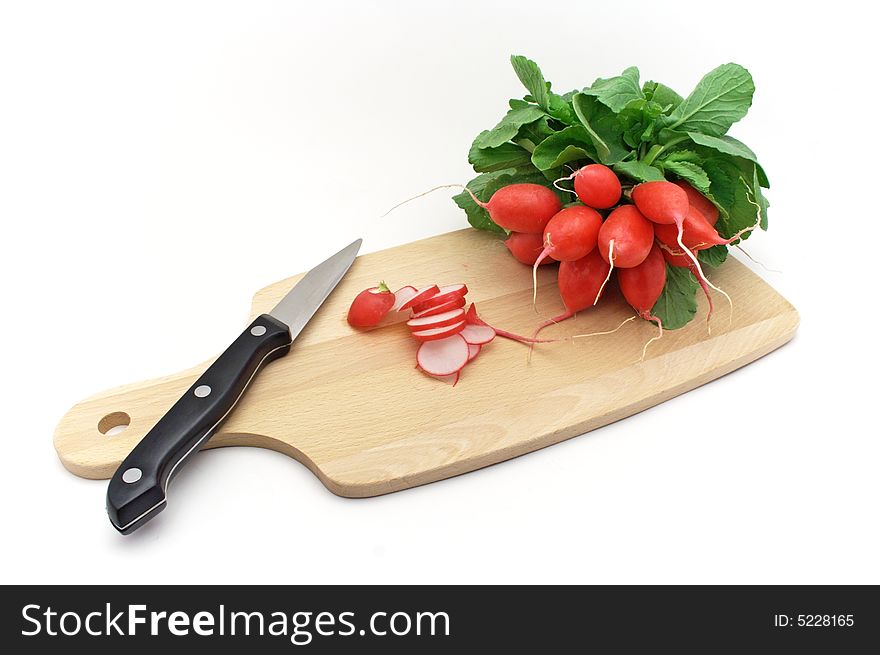 Fresh radishes with knife on chopping board.