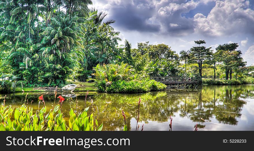 White boat ashore on the far bank of lake in a tropical garden. White boat ashore on the far bank of lake in a tropical garden