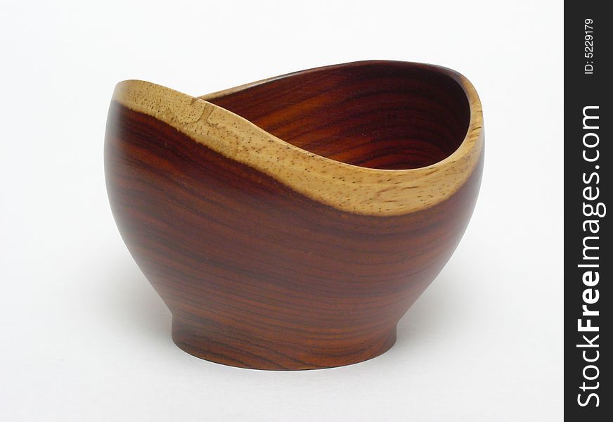 An empty bowl made of Costa Rican rosewood, standing on a plain white backdrop. The bowl is a mid reddish-brown, with light tan edging. An empty bowl made of Costa Rican rosewood, standing on a plain white backdrop. The bowl is a mid reddish-brown, with light tan edging.