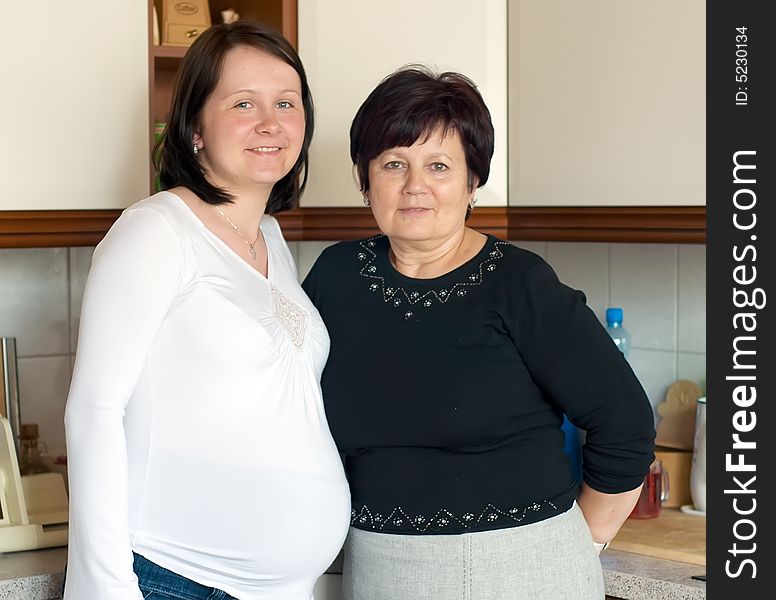 Portrait of mother and pregnant daughter taken in the kitchen