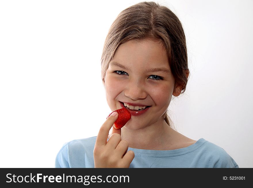 Young white, smiling girls eats strawberry, white background, blue shirt. Young white, smiling girls eats strawberry, white background, blue shirt