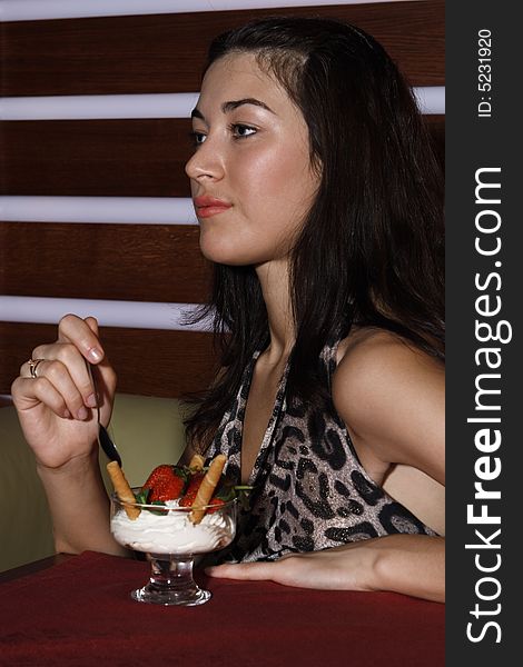 Beautiful girl eating a strawberry and cream in restaurant