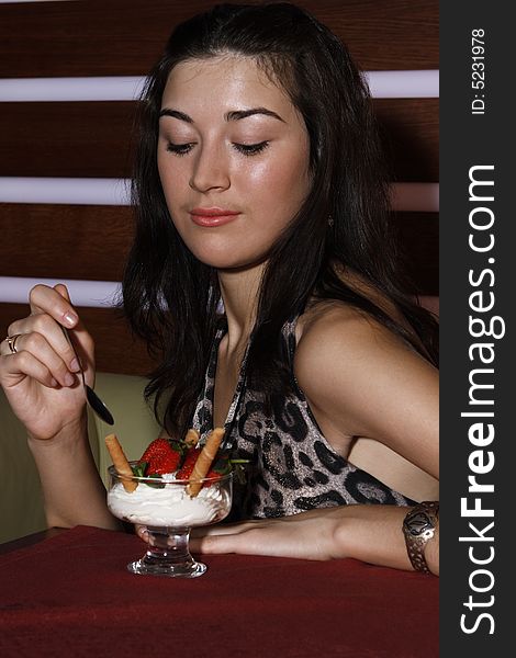 Beautiful girl eating a strawberry and cream in restaurant