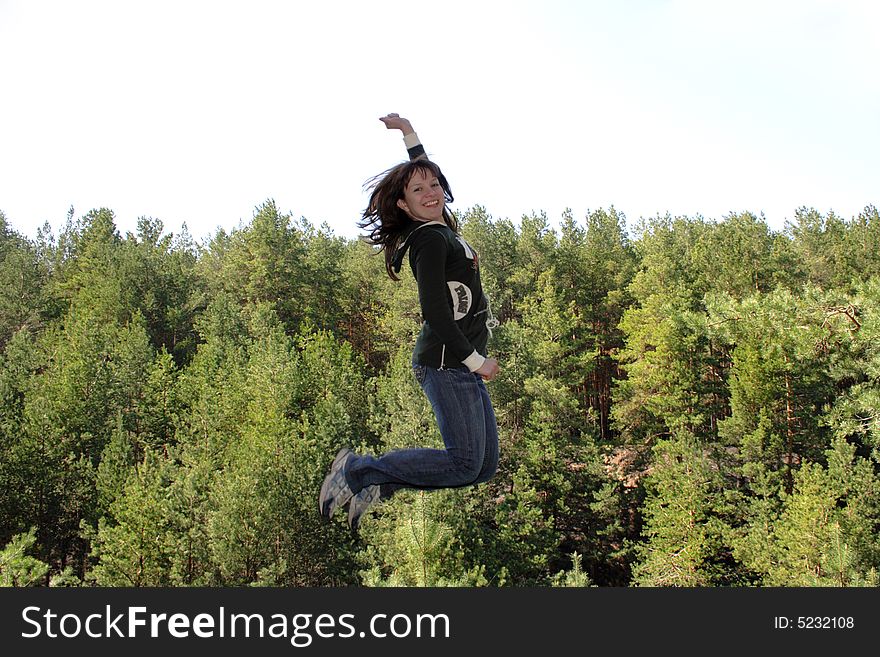 Beauty smiling jumping girl against nature background