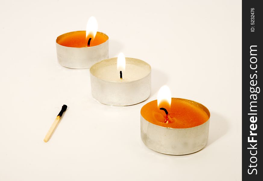 Three candles in a raw lit with a burnt match being near. Three candles in a raw lit with a burnt match being near