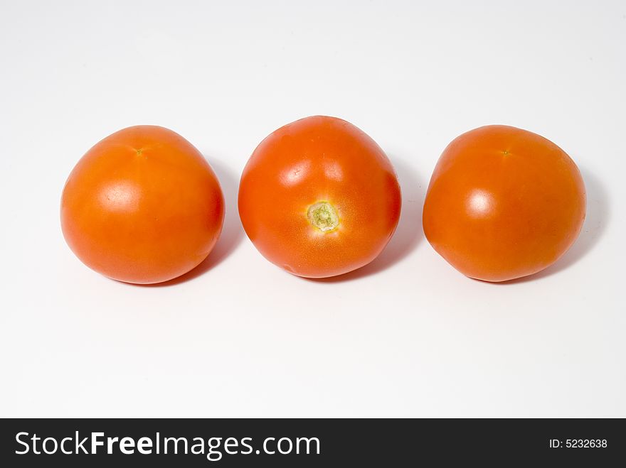 Tomatoes arranged in a raw set over the white background. Tomatoes arranged in a raw set over the white background