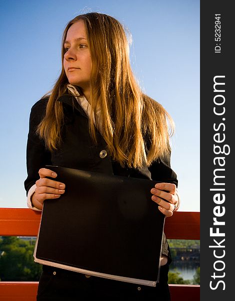 The young businesswoman with a folder on a background of the blue sky