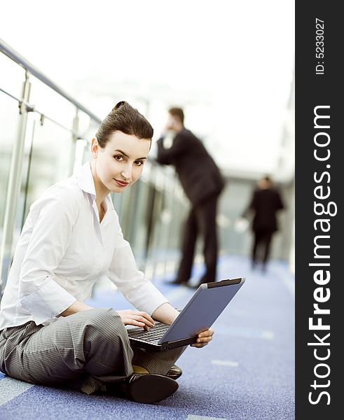 Businesswoman is sitting on the floor with notebook on her lap. Businesswoman is sitting on the floor with notebook on her lap