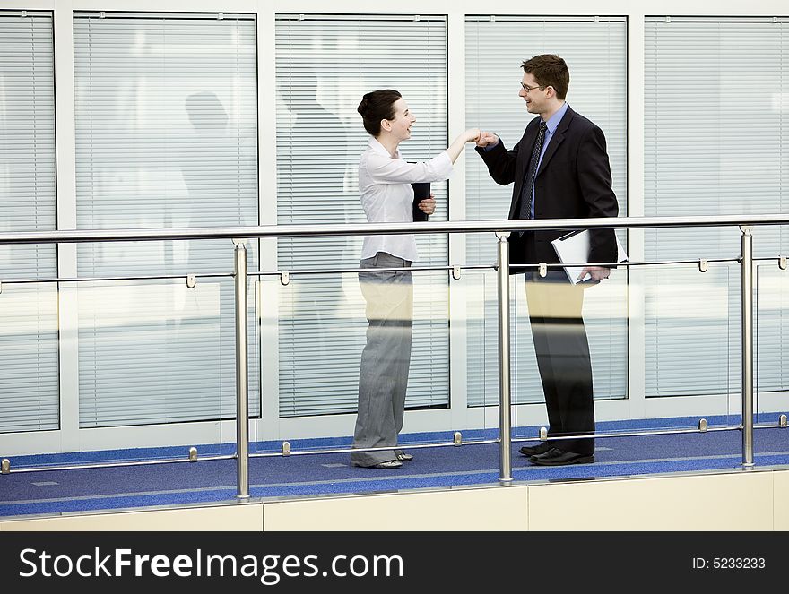 Businessman and businesswoman shaking hands on modern office corridor. Businessman and businesswoman shaking hands on modern office corridor.