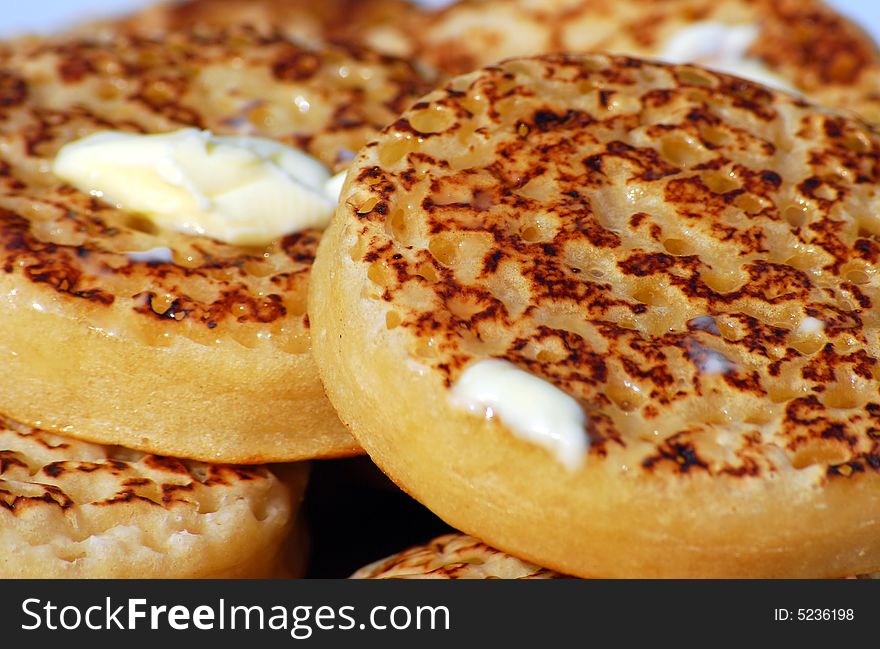 Close up shot of a plate of warm toastedcrumpets,butter melting on them