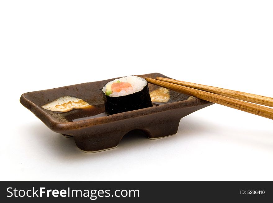 Salmon roll with avocado on plate with chopsticks