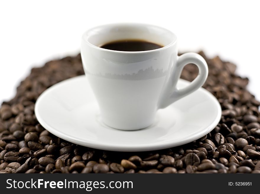 Classic white espresso cup on coffee beans