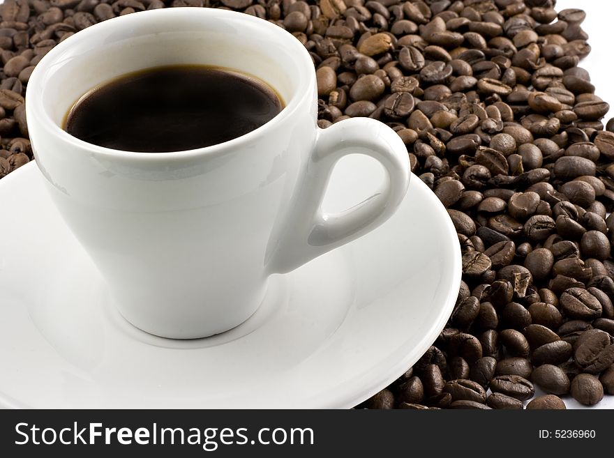 Classic white espresso cup on coffee beans