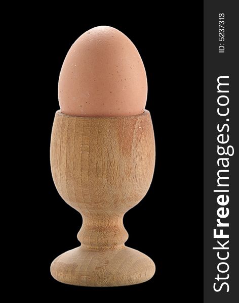 Egg and wood egg cup isolated on black. Egg and wood egg cup isolated on black