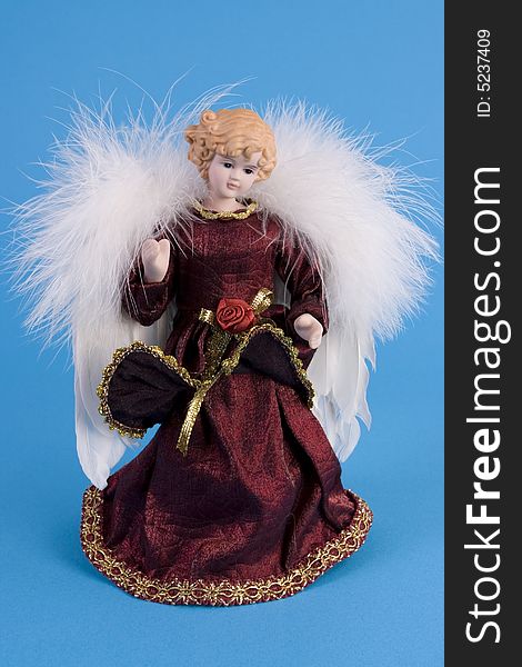 Angel doll with feather wings on blue background