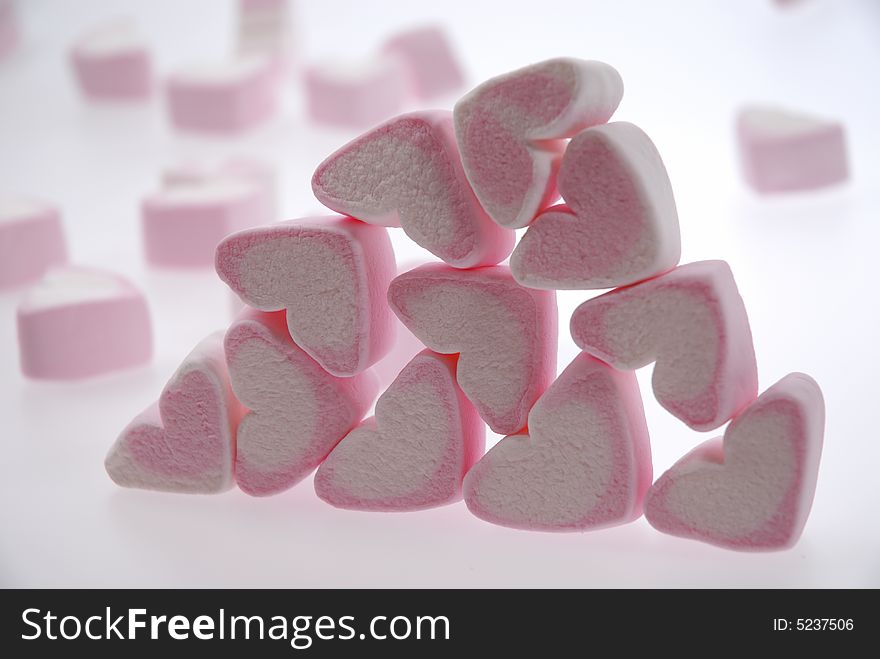 Heart shaped marshmallows in a stack with others floating in the background.