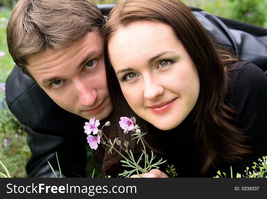 The guy and the girl with a flower lay on a grass. The guy and the girl with a flower lay on a grass