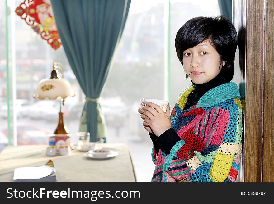 A beautiful young woman holding a cup of hot drink