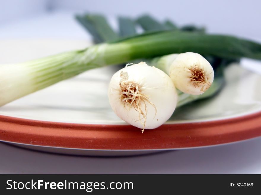 Salad onions on a white plate ready for chopping with shallow depth of field. Salad onions on a white plate ready for chopping with shallow depth of field