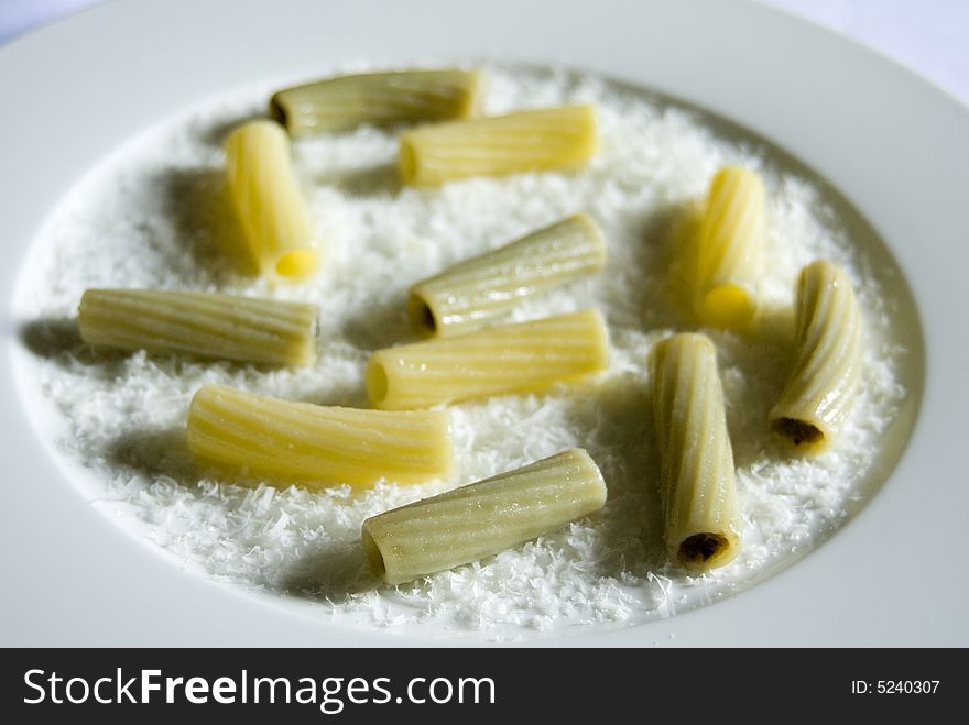 A plate of cooked pasta lighted from the right side to create shadows on the left. A plate of cooked pasta lighted from the right side to create shadows on the left.