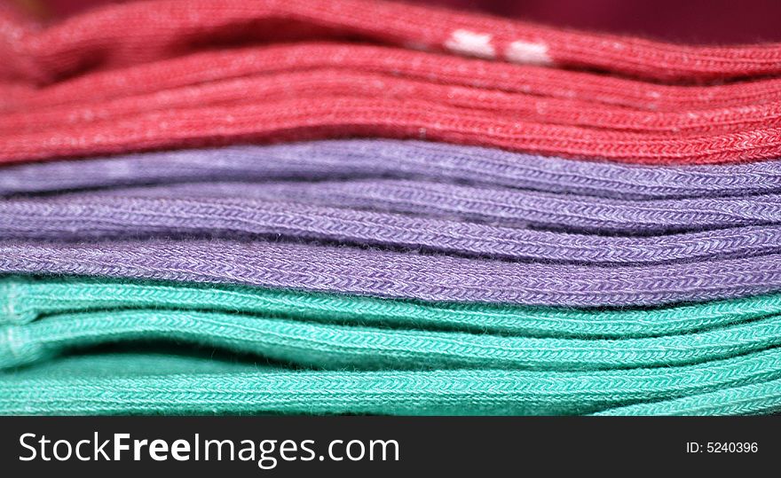 A close-up photograph of a pile of three pairs of socks