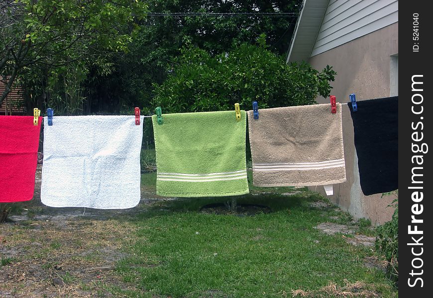 A line of colorful face cloths are hanging on a wash line. A line of colorful face cloths are hanging on a wash line