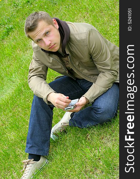 Man on green grass with phone in hands