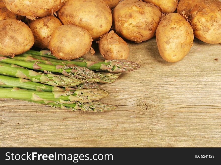 Asparagus and new potatoes on old wood background. Asparagus and new potatoes on old wood background