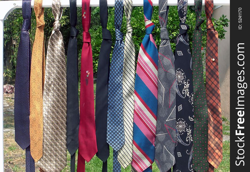 A line of men's colorful neckties are on a rail. A line of men's colorful neckties are on a rail