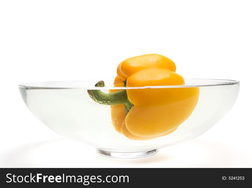 Yellow paprika floating in vase with water over white background